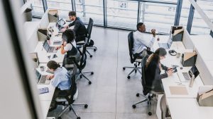 Modern open office with employees working at desks, collaborative workspace environment"